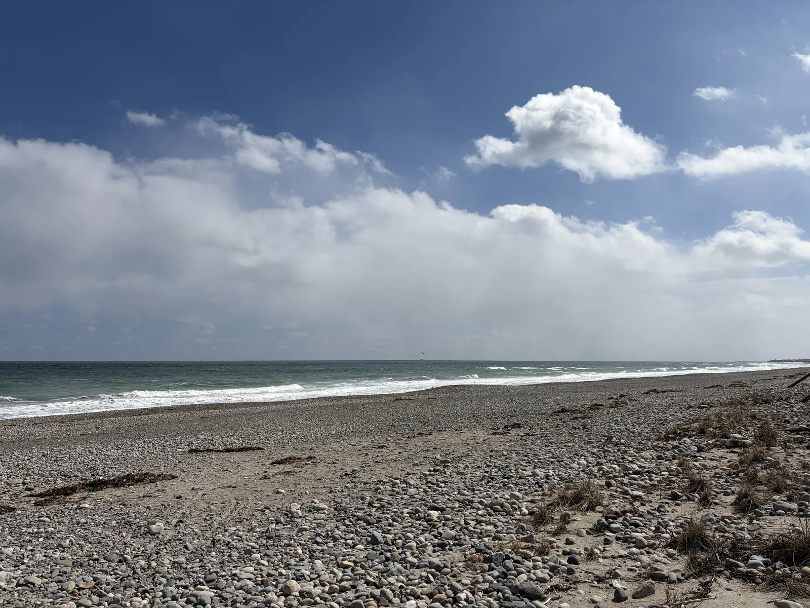 Waves rolling onto a pebbly beach under a big sky